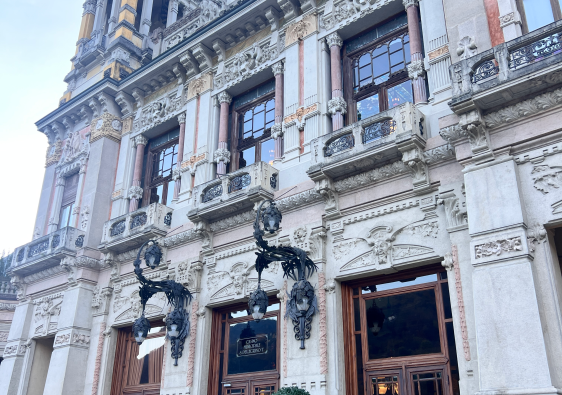 Elegant historic building with ornate architecture, tall windows, and decorative details in San Pellegrino Terme, Italy, under a clear blue sky