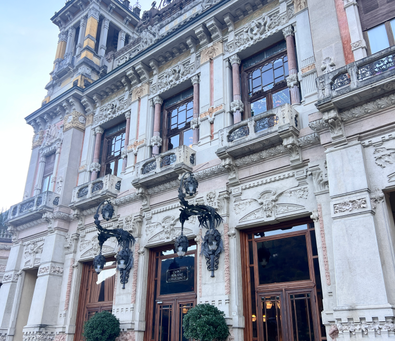 Elegant historic building with ornate architecture, tall windows, and decorative details in San Pellegrino Terme, Italy, under a clear blue sky